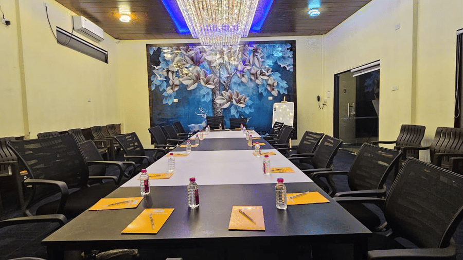 Professional boardroom setup with a long dark wood table, leather chairs, and a decorative tree mural - DAN Resorts & Weddings, Palghar