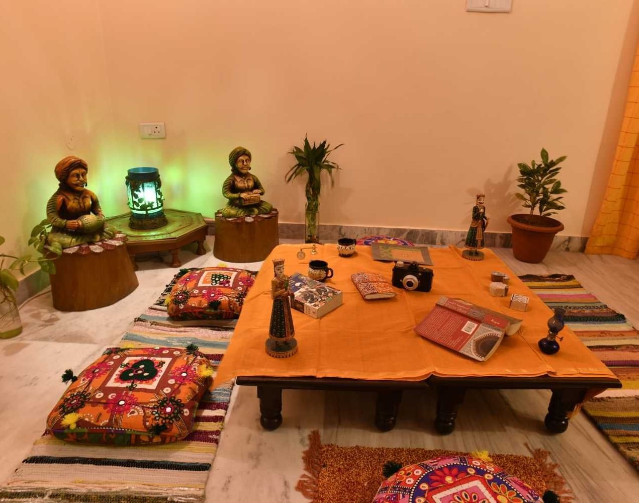 A cosy traditional low seating area with floor cushions and a wooden table, creating a warm indoor dining  at Jaypore 360 Homestay.