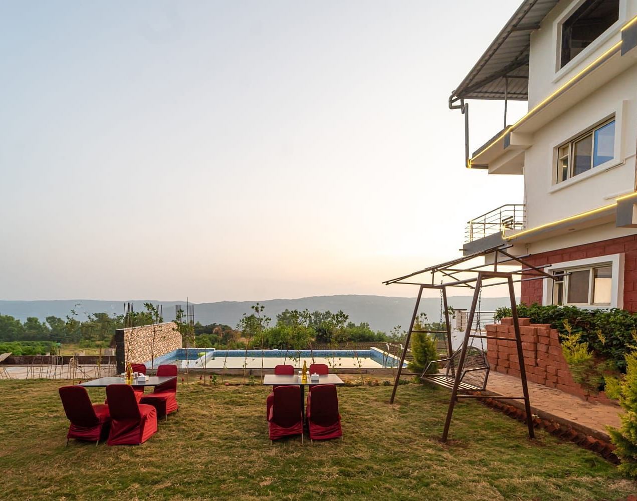 Outdoor lawn area next to a swimming pool featuring seating arrangements and a swing.