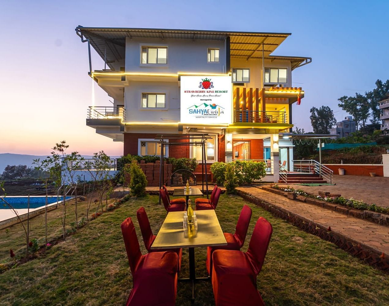 An exterior view of Strawberry King Resort, Mahabaleshwar with outdoor seating.