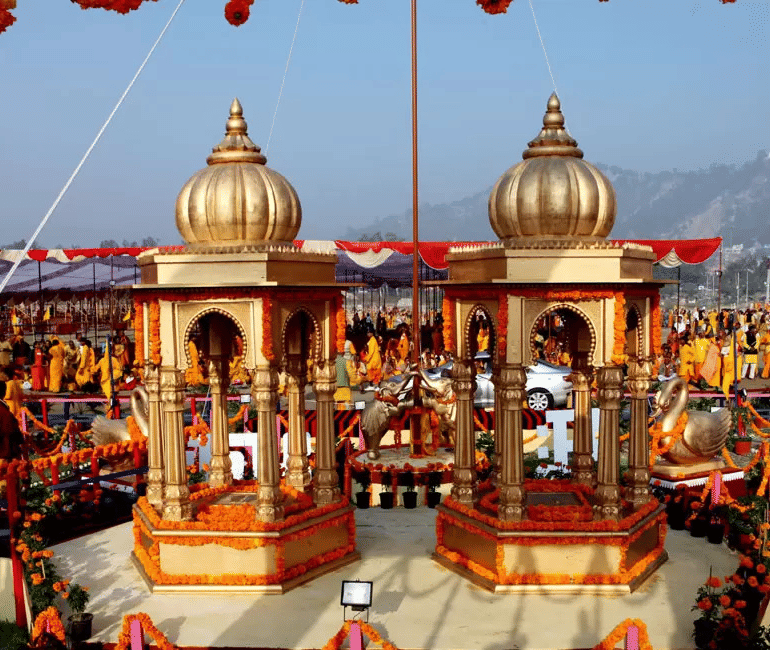 People gather around temple structures with decorated arches and lamps under a clear sky