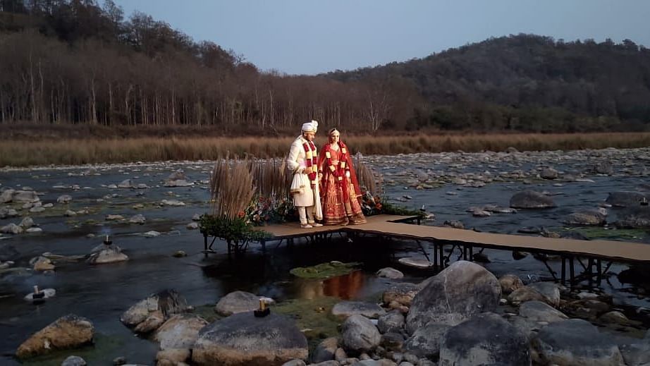An image of bridge and groom standing at the isle in the middle of a river