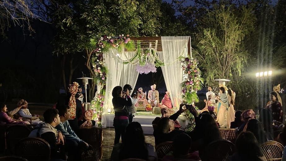 An image of outdoor banquet hall with decorated seats and a table placed at the centre