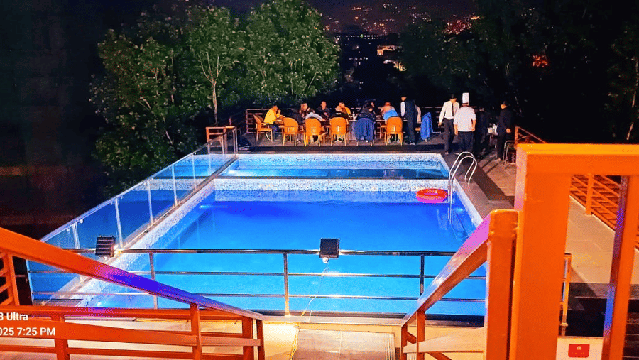 Dining setup for a large group on the patio of the illuminated swimming pool at Mandala Norling Lords Prime, Kathmandu.
