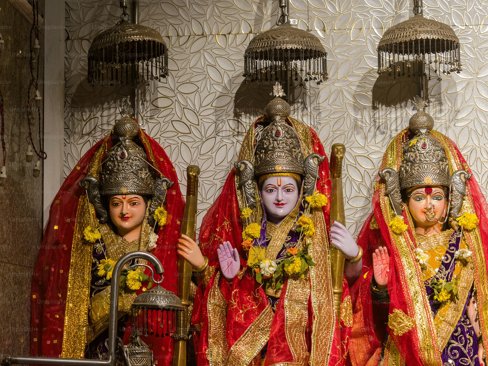 Image of Shiva, Laxman and Sita coverd in shawl and flower garlands