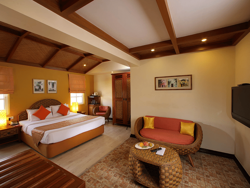 A spacious bedroom with a king bed and a sitting area at The Richmond Puducherry.