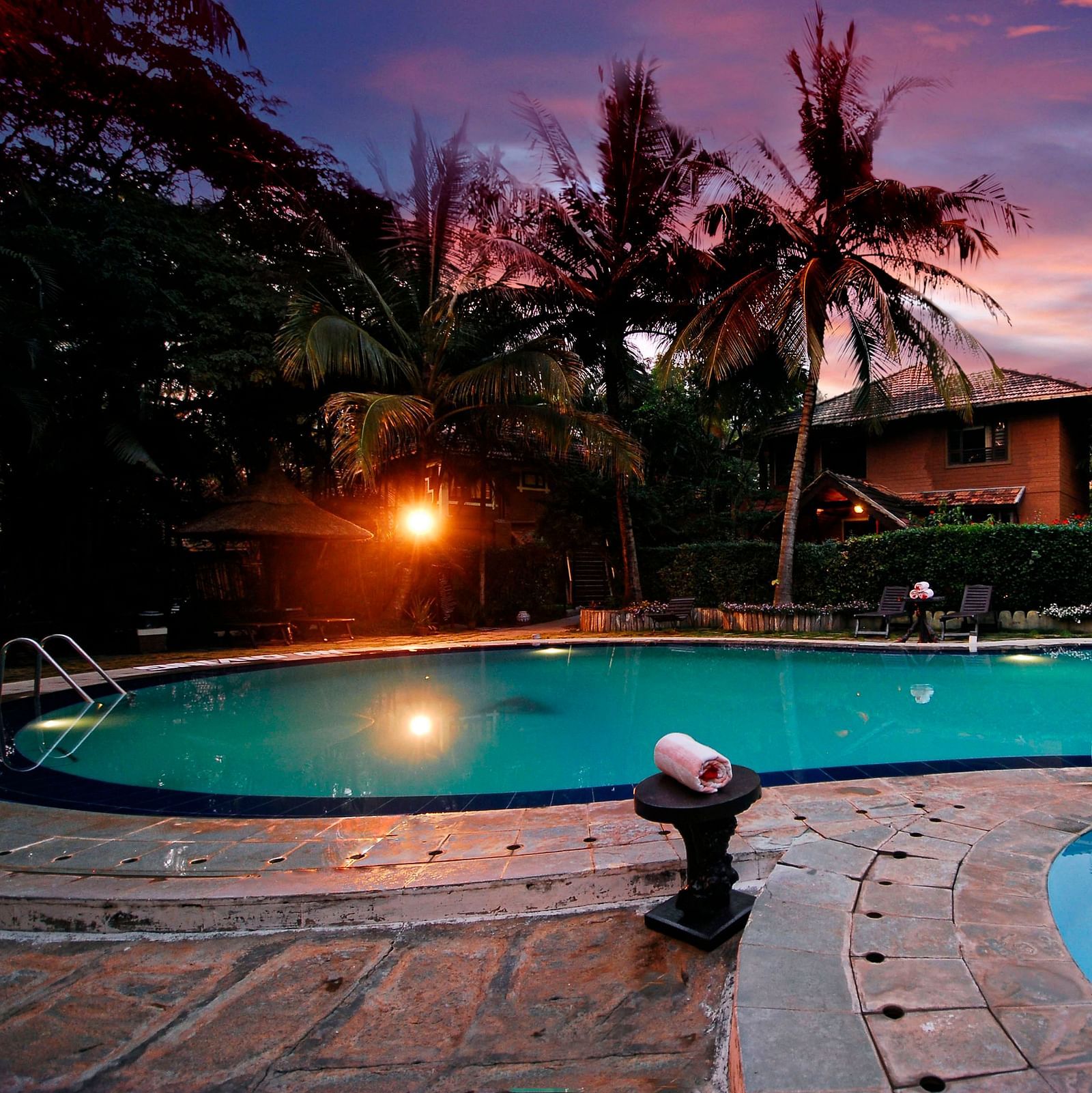 An image of a swimming pool in the night - Hoysala Village Resort, Hassan.