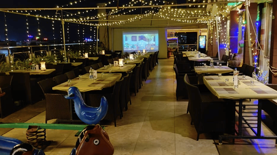 The rooftop restaurant at Hotel Rockfort View, Trichy with aligned chairs and tables and warm lighting.