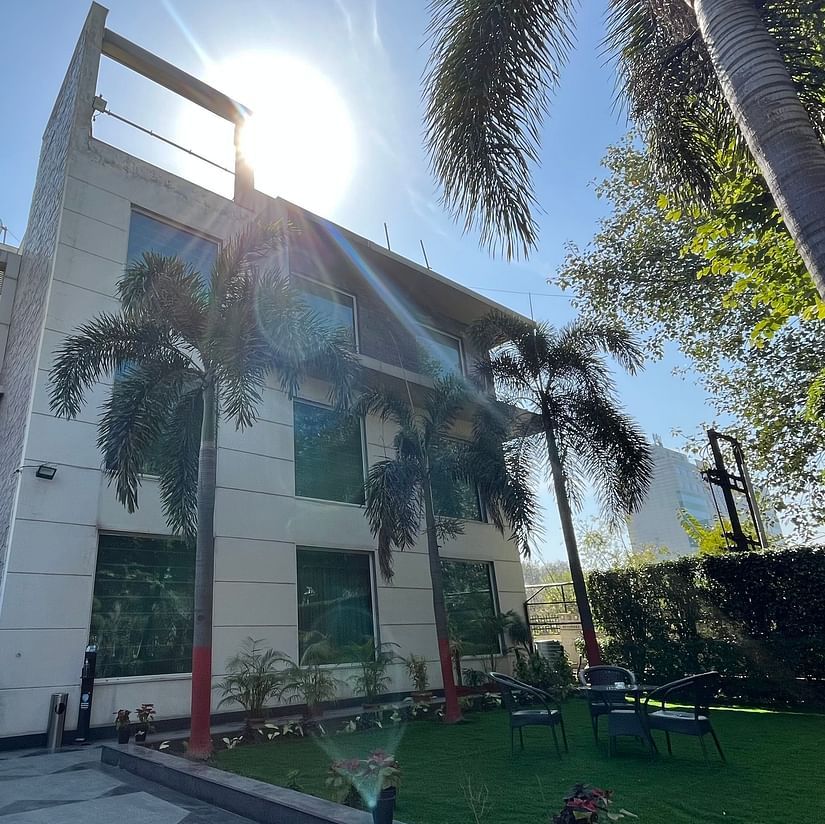 facade view of Yuhi Mansions surrouded by green coconut trees and a beautiful lawn outside the building that showcases tea-table and chairs for enjoying the view1