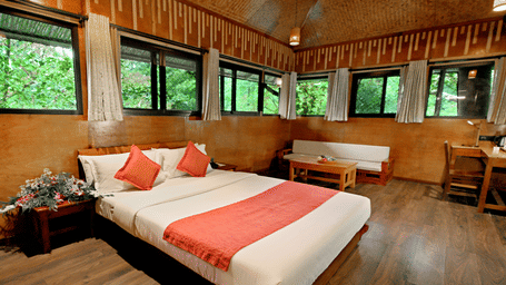 Room with multiple windows and a bed, offering lush forest views at Vythiri Resort, Wayanad