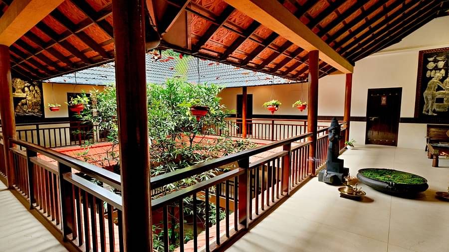 Outdoor corridor with wooden railings and greenery view at Vythiri Resort, Wayanad