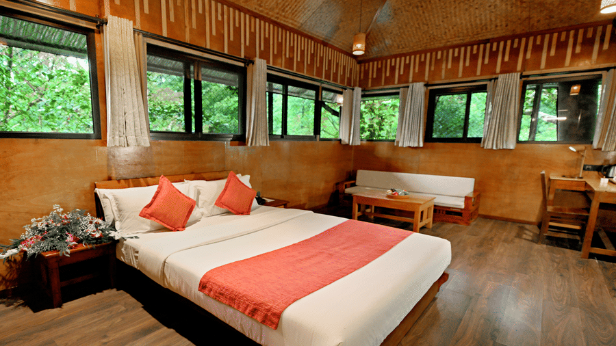 Room with multiple windows and a bed, offering lush forest views at Vythiri Resort, Wayanad