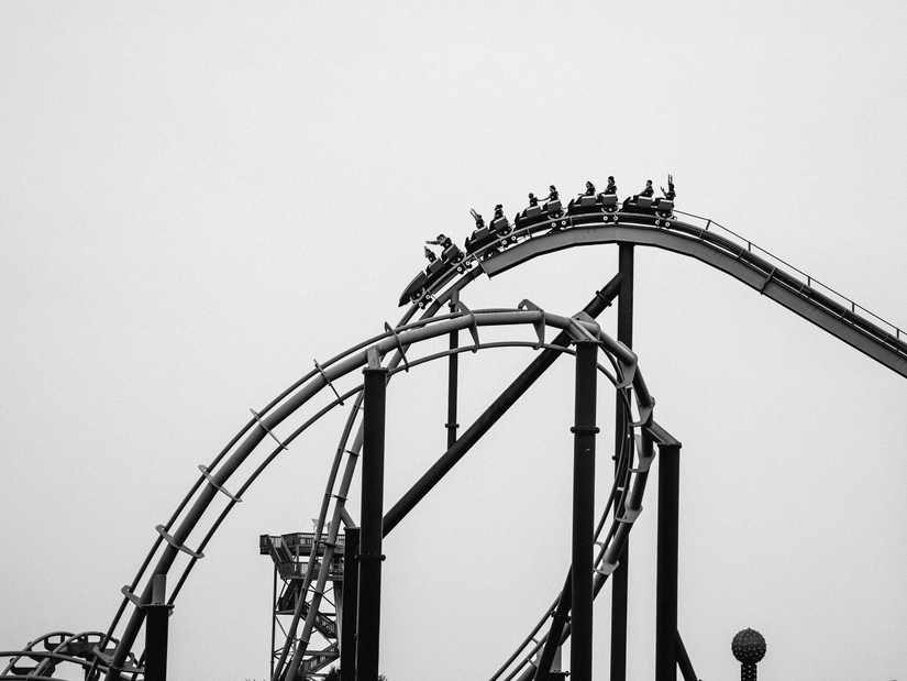 A roller coaster with many people sitting inside the carts, just about to do a free fall down