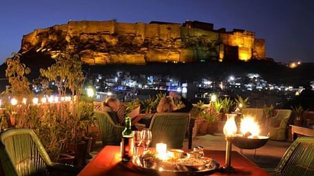 Terrace at Haveli Inn Pal decorated with warm lights and a table with well cushioned chairs placed around it