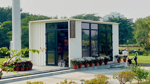 A solitary building next to a flag pole with a manicured lawn area next to it - Karma Lakelands.