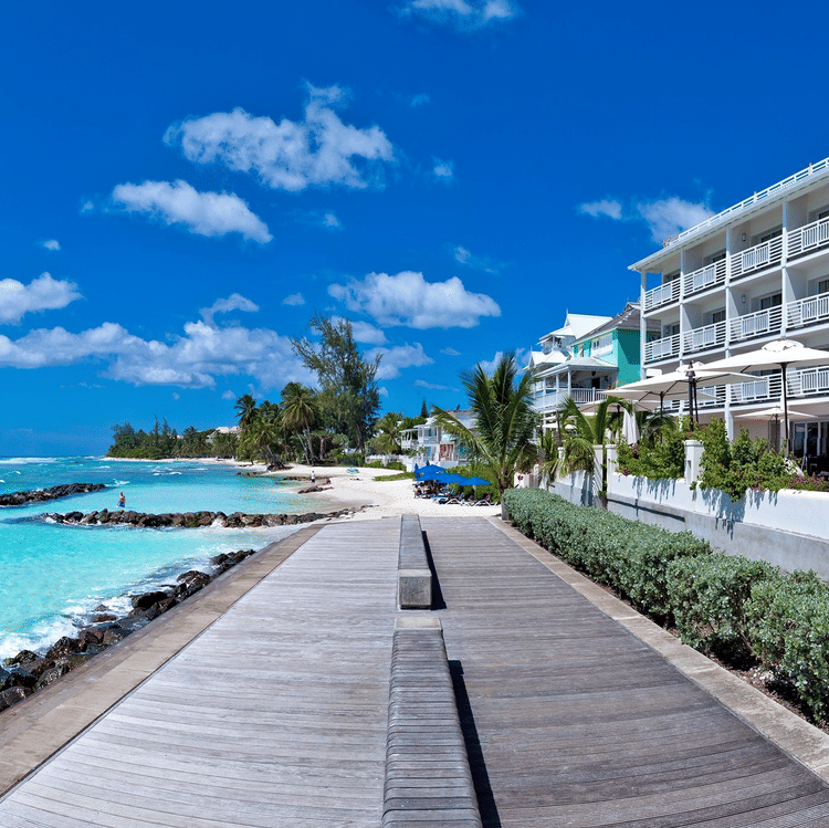 Oceanfront pathway beside The Soco Hotels with clear turquoise water seen during a bright sunny sky.