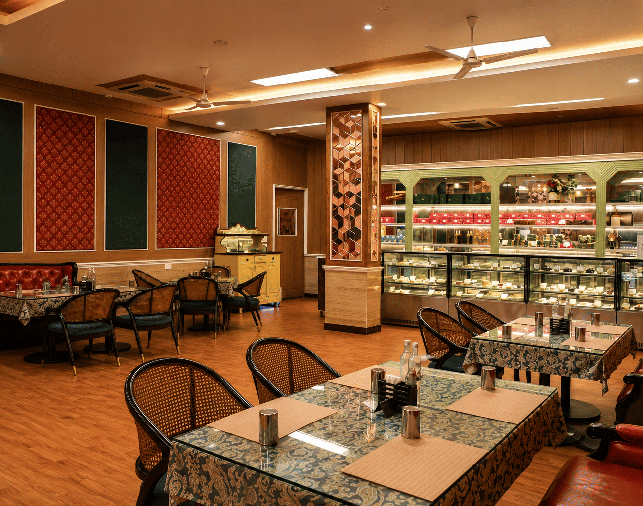 Super Snax pastry shop with display counters of cakes and sweets, gift boxes on shelves, cane chairs and sofa seating at MAYFAIR World Cup Village, Rourkela.