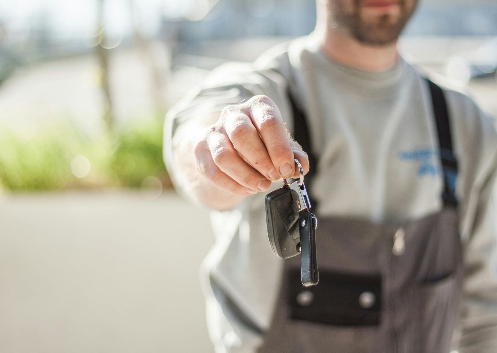 a close up shot of a person handing over car keys with the background blurred.