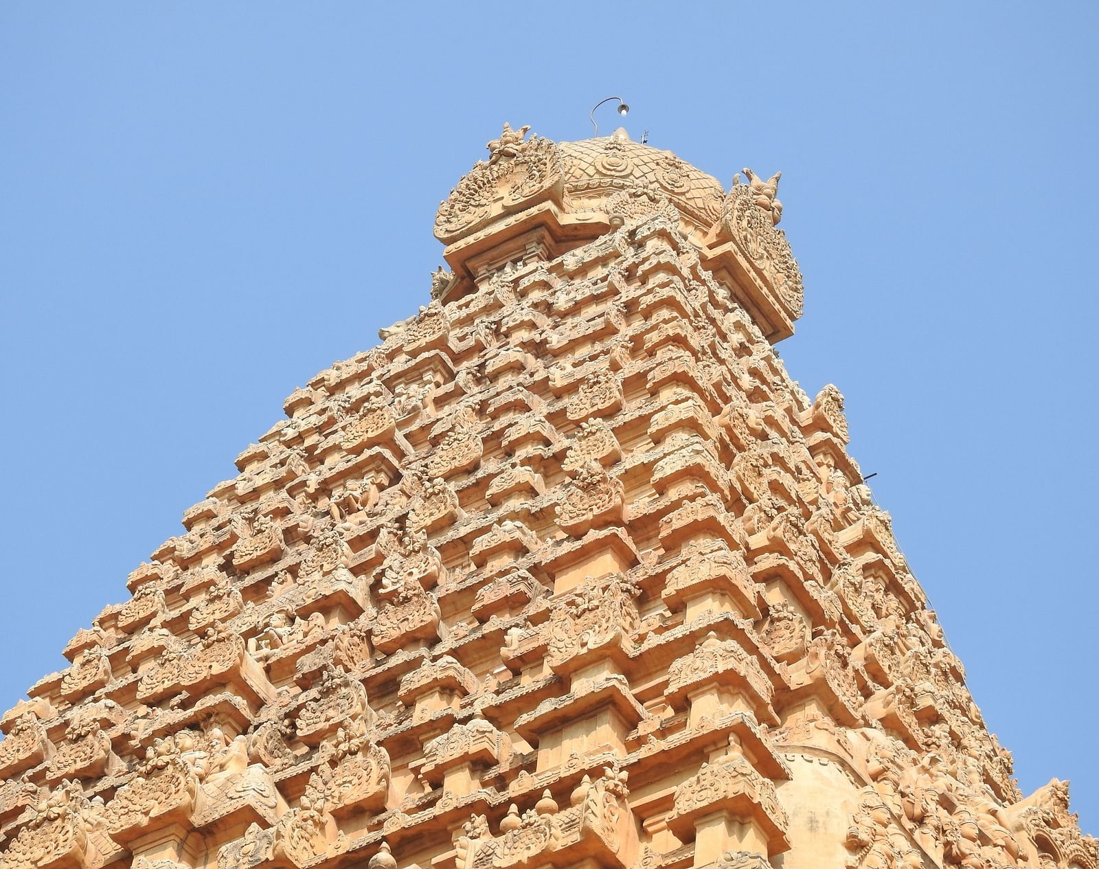 A view from below of a temple's roof with intricate architecture on it.