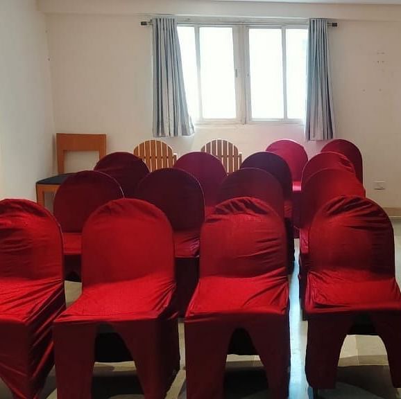 Spacious seminar hall at Lords Eco Inn Dahej featuring red fabric chairs arranged in rows with natural lighting from large windows