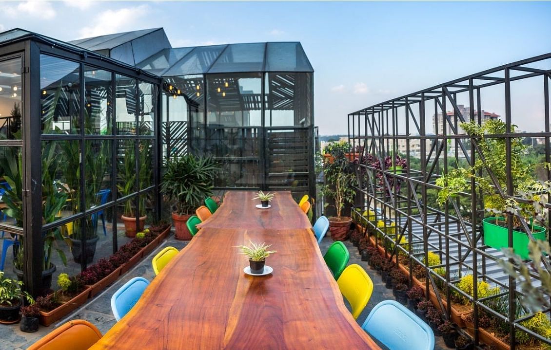 a long wooden dining table surrounded by bright colourful chairs.