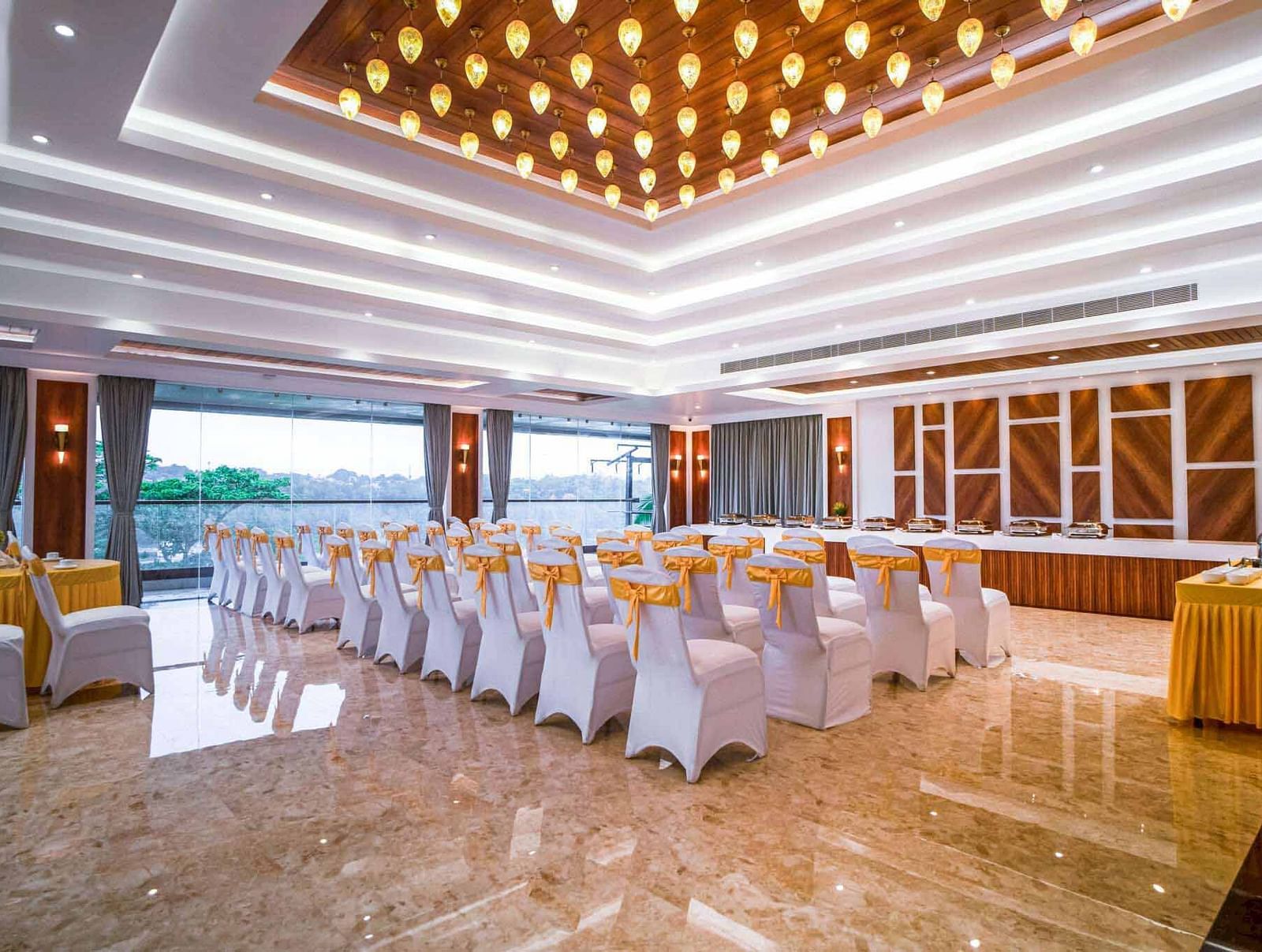 A well-lit event hall at Mansha Palace is arranged with rows of draped chairs facing a stage area.