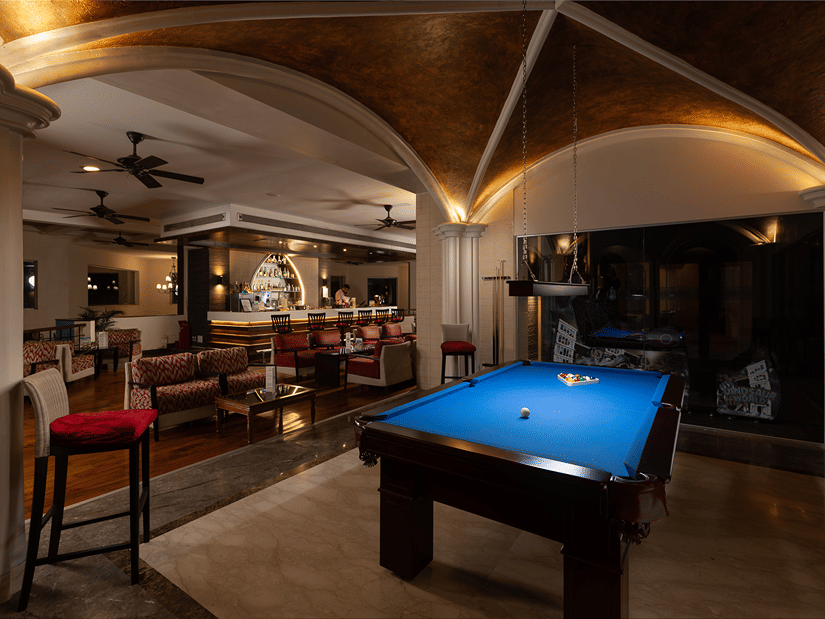A dimly lit room featuring a blue coloured pool table in the middle at Kenilworth Resort & Spa, one of the team-building activities in Goa