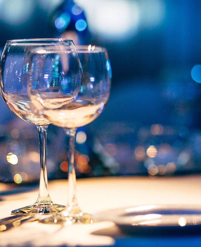 Wine glasses, cutlery, and a plate placed on a dining table illuminated by warm lighting - Brewery Gulch Inn & Spa