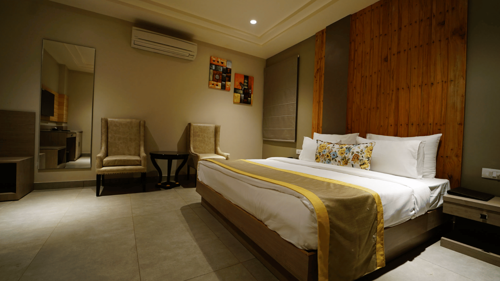 A luxury suite with a king size bed, wooden accent wall, and spacious seating area at Five Elements Hotels.