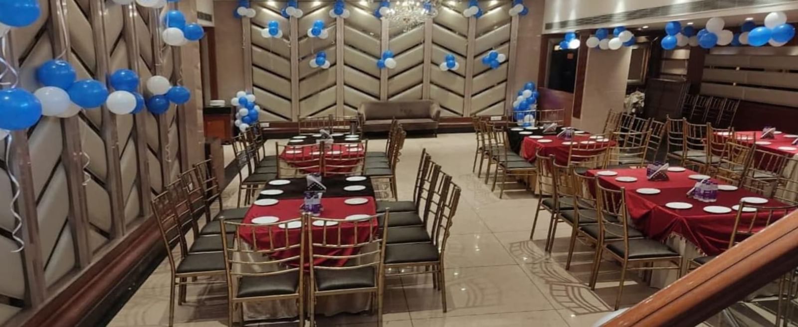 BluSalzz Select - City Centre, Amritsar banquet hall decorated with blue balloons and red table settings.