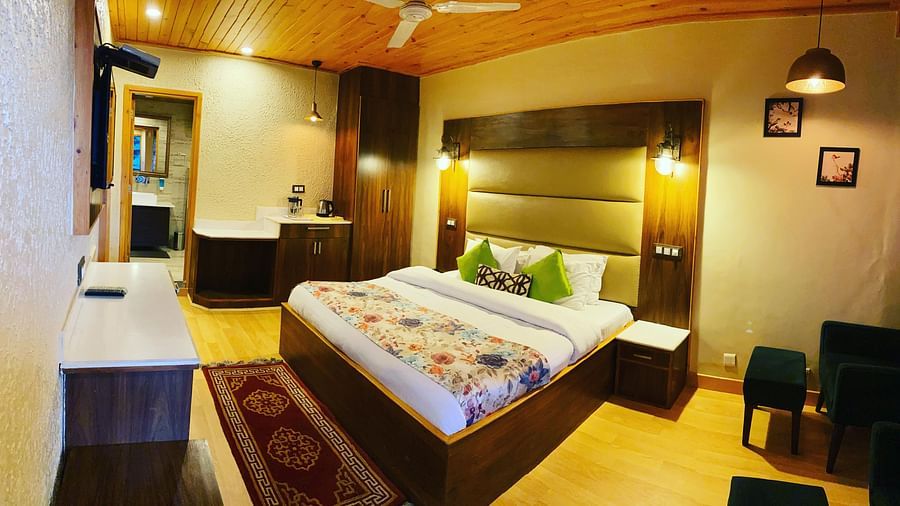 A room with a bed and TV on the wall | Mongas Hotel & Resort, Dalhousie