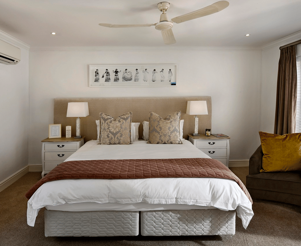 A double bed with a ceiling fan hanging over it in a bedroom.