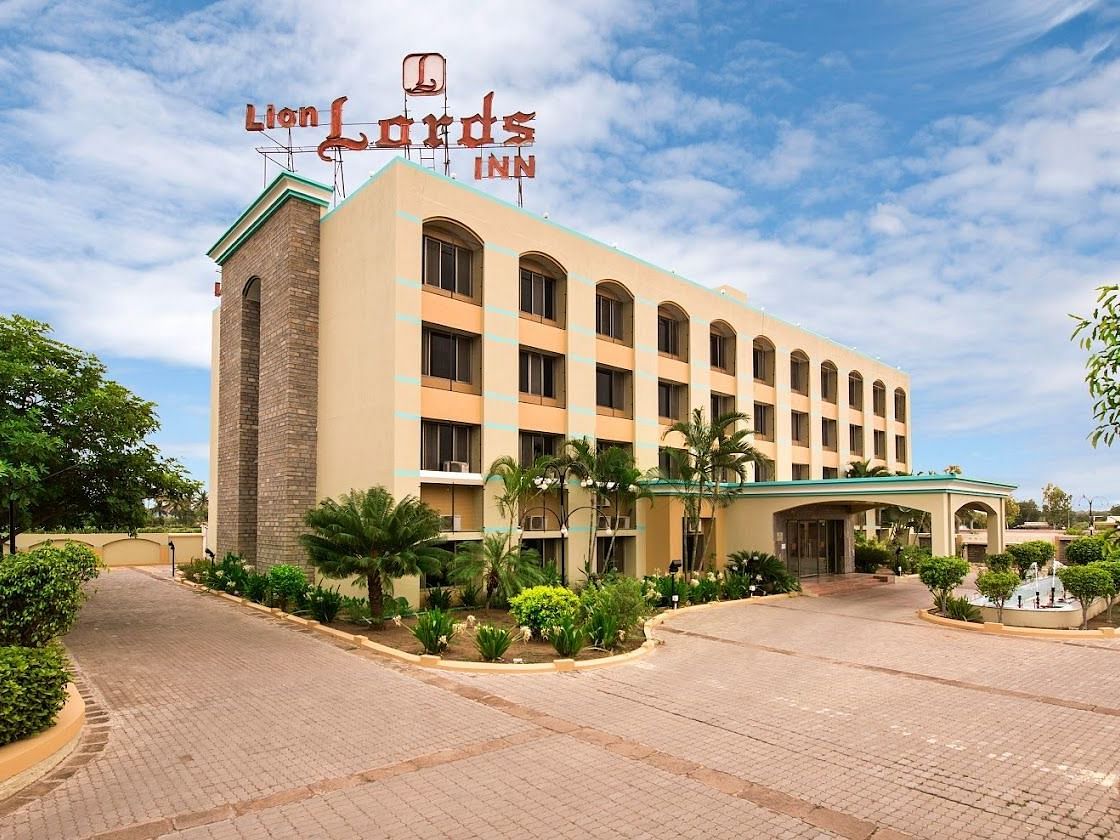 The front of a light-coloured building visible on a sunny day - Lion Lords Inn Rajula