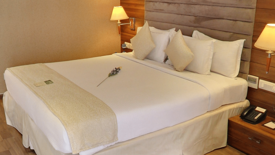 Bed with white sheets and a cream bed scarf