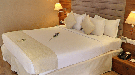 Bed with white sheets and a cream bed scarf