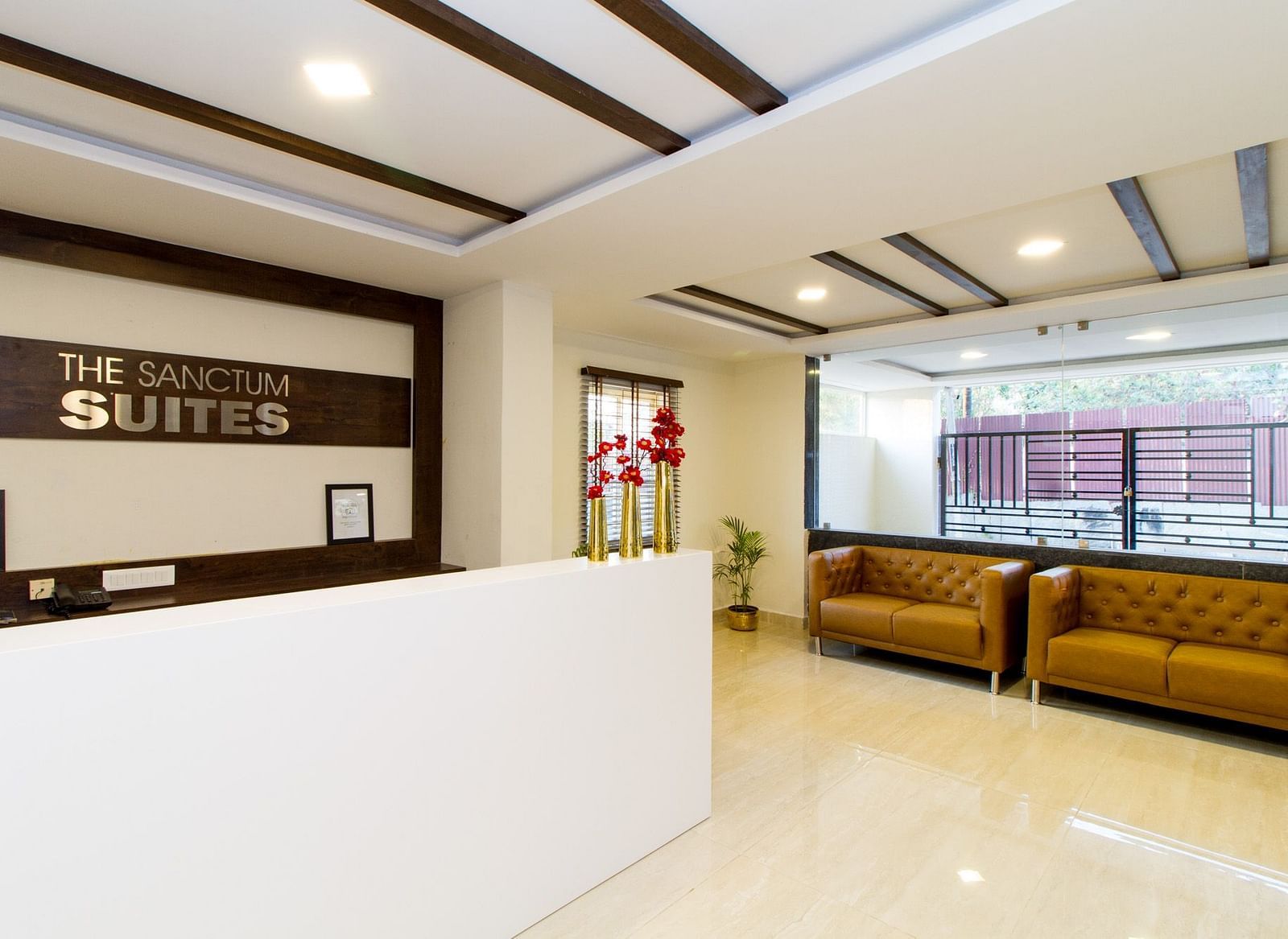 A hotel reception area featuring a white desk and two sofas at Sanctum Suites Whitefield, Bangalore.
