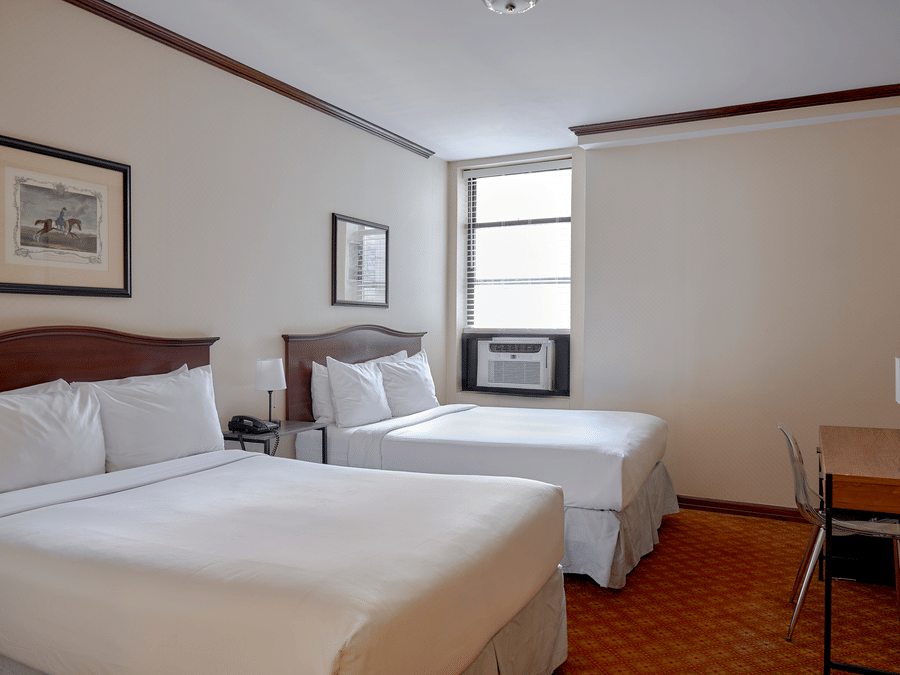 Room at Night Hotel Broadway showing two beds, desk area, framed art, and window.