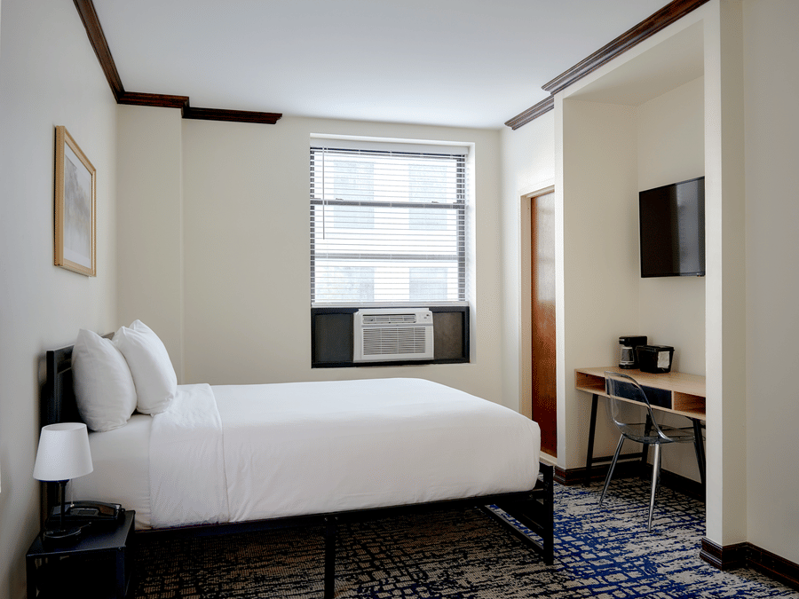 Compact room at Night Hotel Broadway with a double bed, desk, and wall-mounted TV.