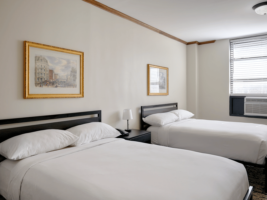Night Hotel Broadway guest room featuring two double beds, framed artwork, and window.