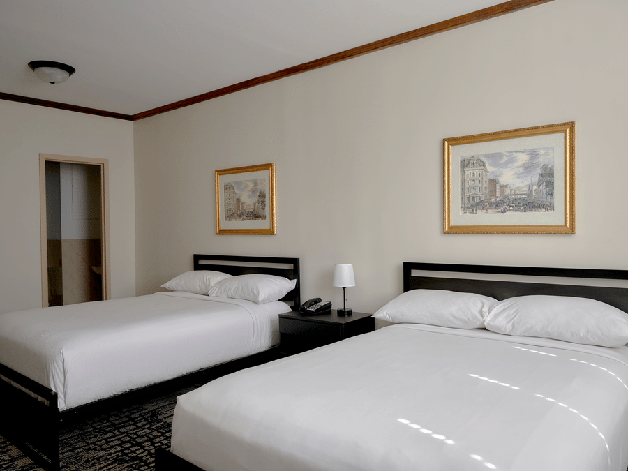 Spacious room at Night Hotel Broadway with two double beds, wall art, and bedside tables.