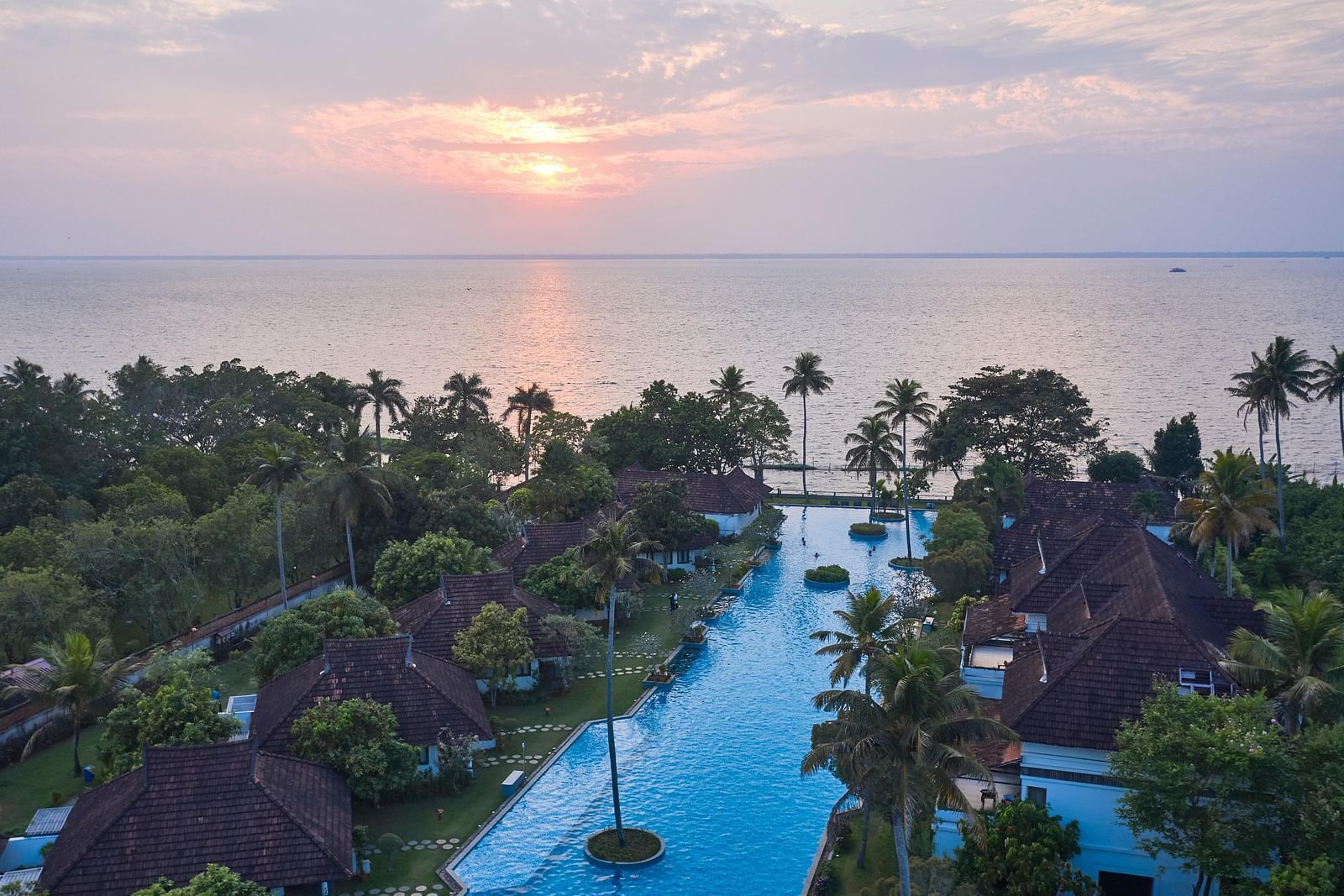 Aerial view of Rhythm Kumarakom with a swimming pool covered by coconut trees.