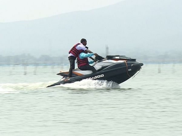 A person jet skiing on a lake with a mountain in the backdrop