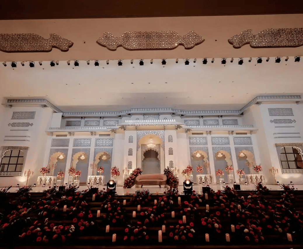 A large white palace building with lit windows and guests seated outside on the lawn at Beelwa Palace, Jaipur.