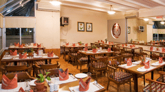 An overview of Kamat's Veg Restaurant, the best veg restaurant in Silvassa, with modern ambience and four chair seating, an AC and a large mirror inside at VITS Kamats Resort, Silvassa.