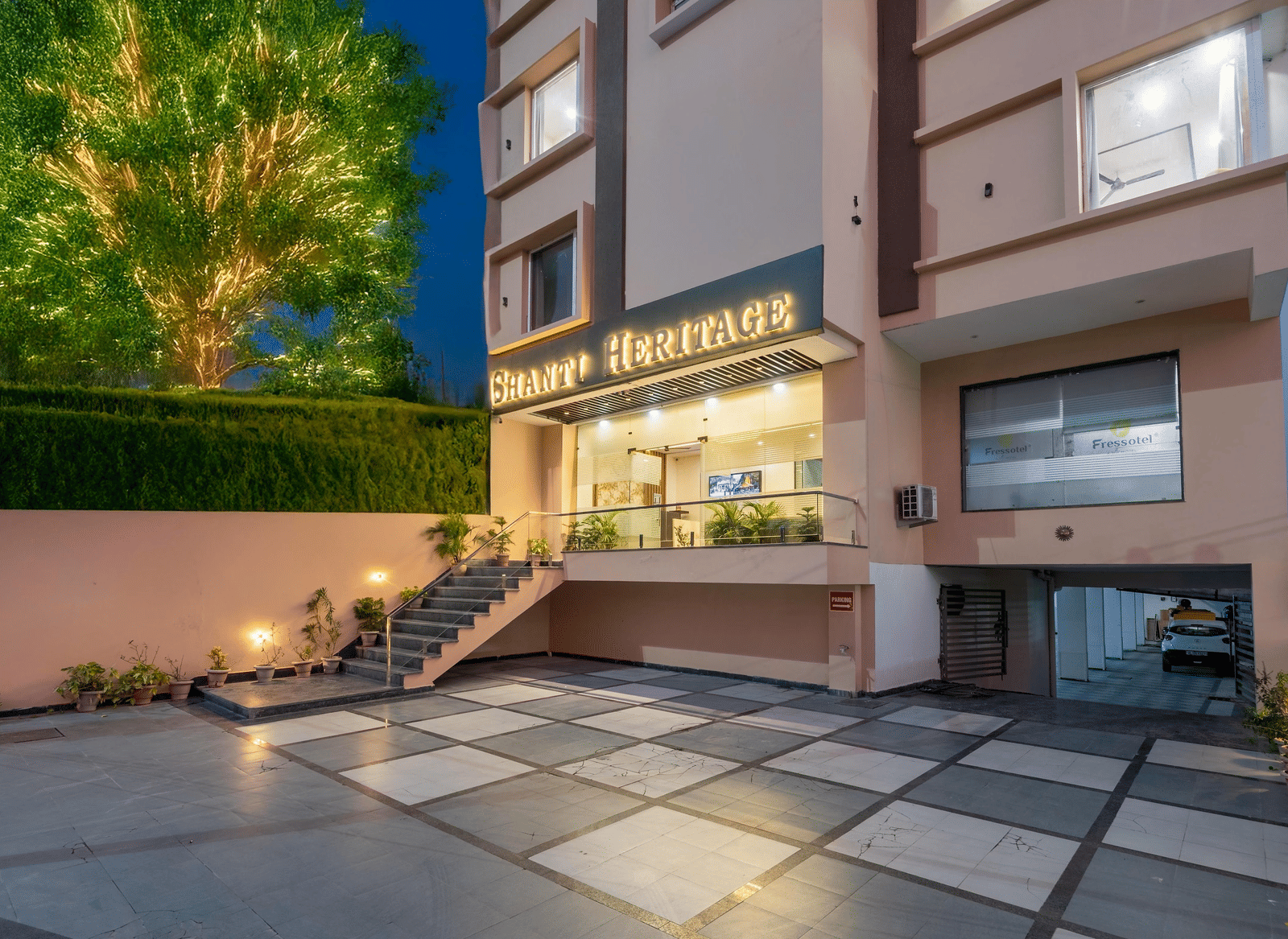The hotel building entrance and paved driveway at late evening showing trees at Perfectstayz Premium Shanti Heritage, Haridwar