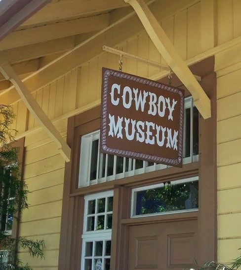 A sign with Cowboy Museum hung outside a window - The Groveland Hotel.