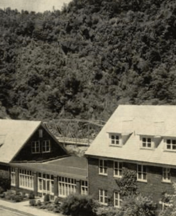 an old black and whit image of the facade of our resort featuring a mountain range behind the resort - Historic Tapoco Lodge