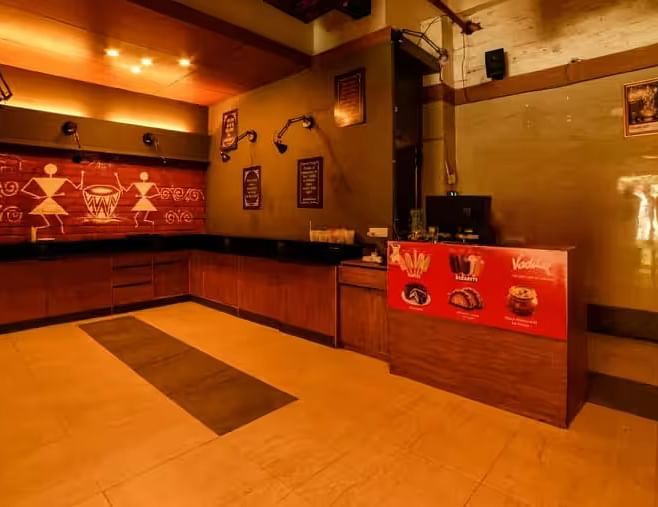 View of the entrance area with warm lighting to Mumbai Masala Restaurant - Max Hotel Prayagraj.