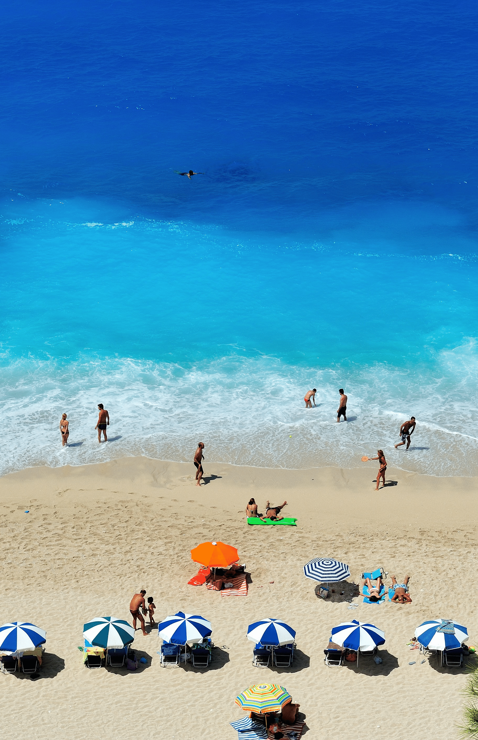  Aerial view of the beach, showing people relaxing on the shore and swimming in the water