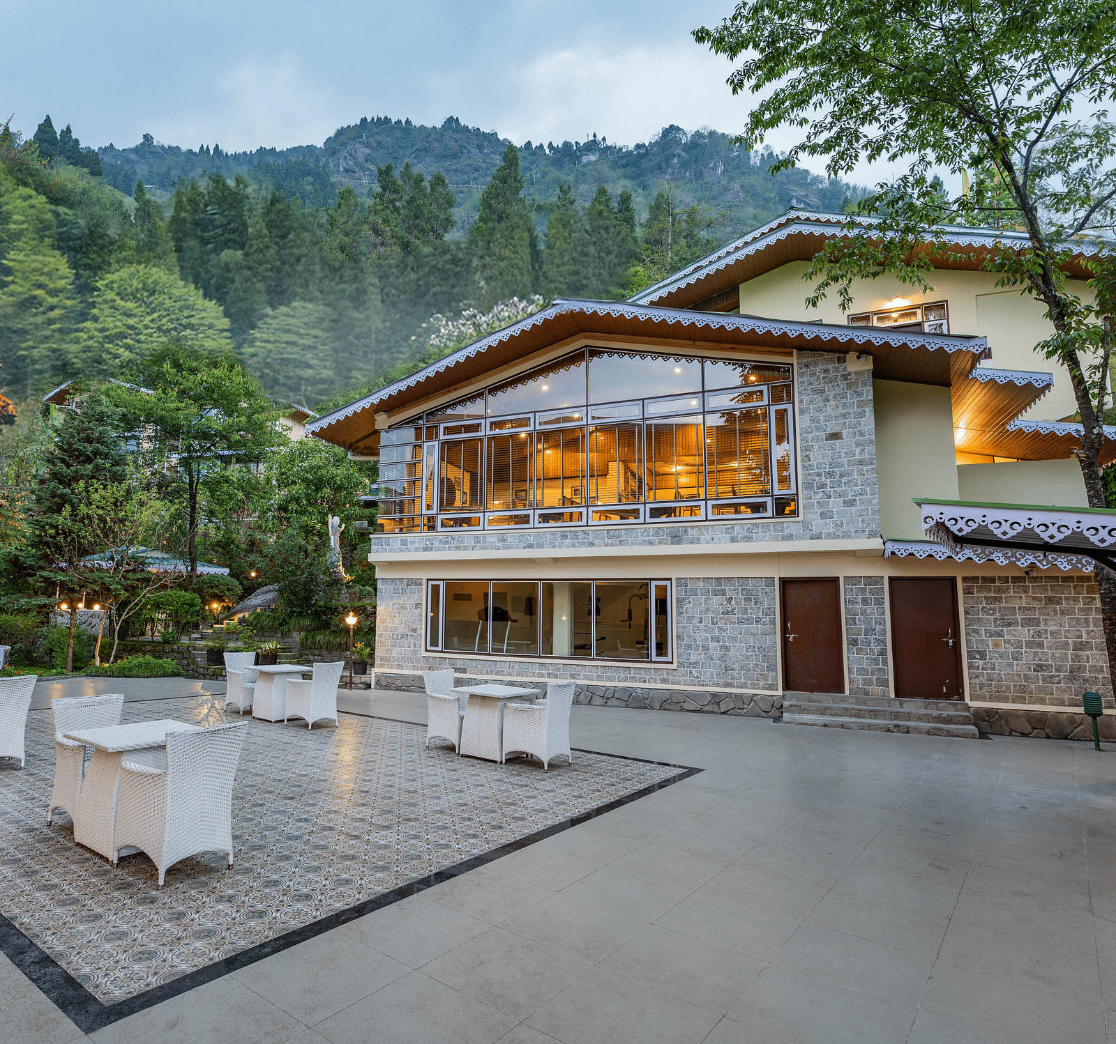 Facade of Summit Norling Resort & Spa, Gangtok with trees on the side and mountains in the background.